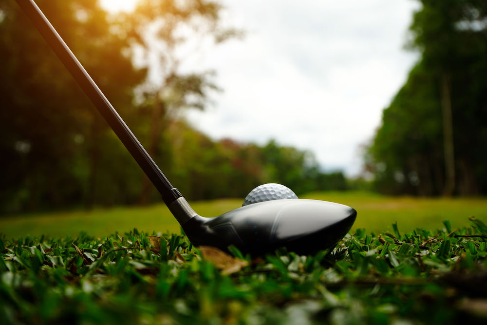 Close up on a golf ball and club about to strike it