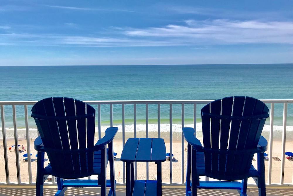two blue chairs on balcony overlooking gulf coast