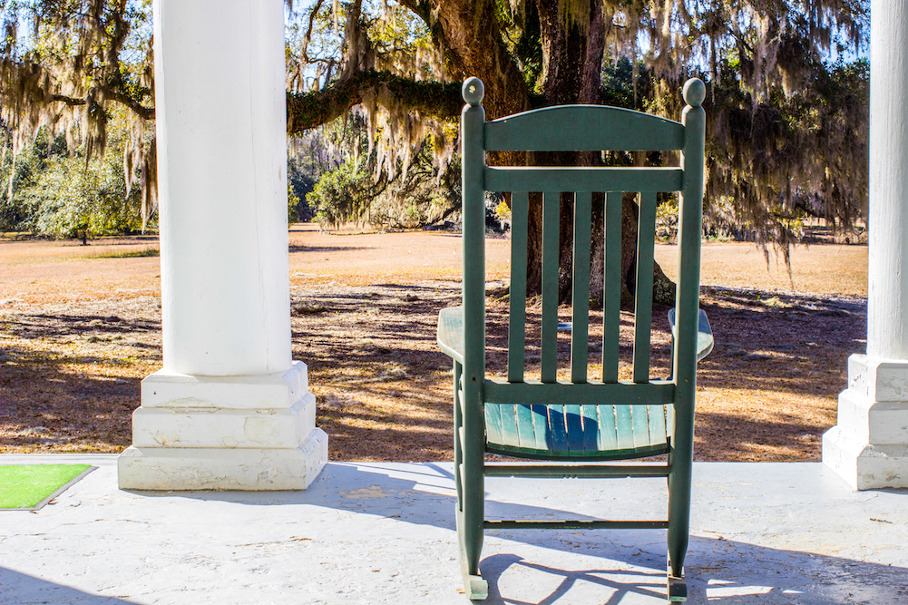 rocking chair on porch with live oak in background