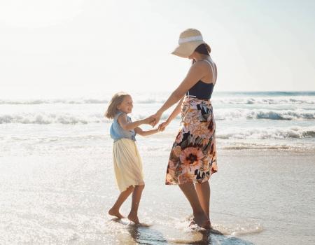 mother and daughter dancing on the beach